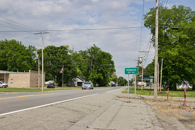 Two-lane highway through town with "Humphrey" road sign on its right side