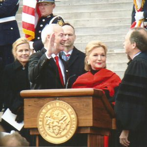 Mixed crowd of officials including one in judge's robes on steps of capital during inauguration ceremony