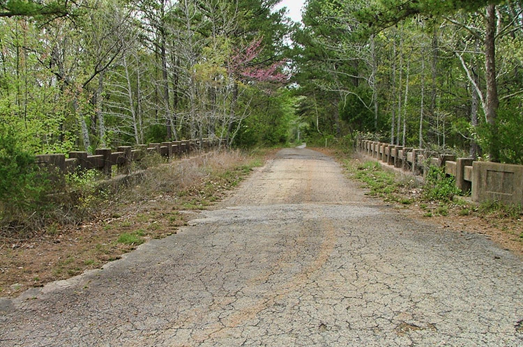 Looking across rural highway bridge with trees on both sides