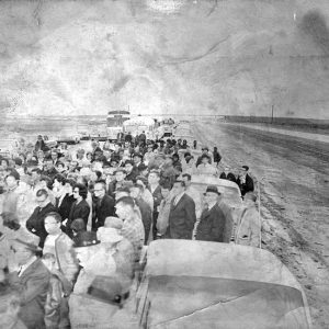 Crowd of white people standing with cars and buses on interstate