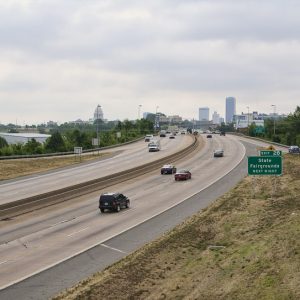 Busy interstate with State Capitol building and tall buildings in the distance