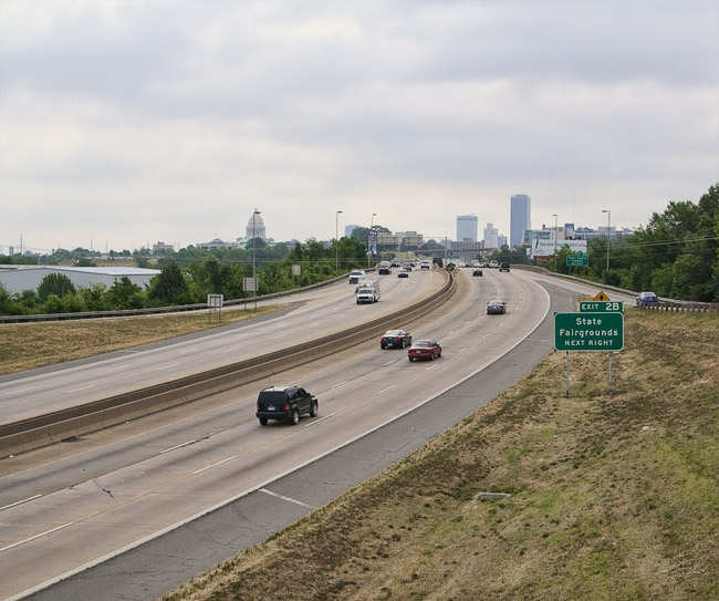 Busy interstate with State Capitol building and tall buildings in the distance