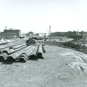 Pile of sheet metal on construction site with multistory buildings in the background