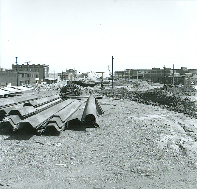 Pile of sheet metal on construction site with multistory buildings in the background