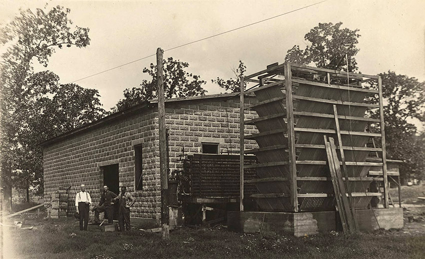 Men standing beside large brick structure
