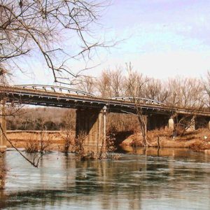 Concrete bridge over a river with trees and blue skies