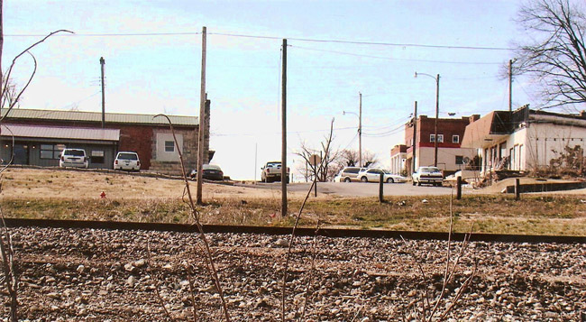 Railroad tracks with town buildings and cars in the background