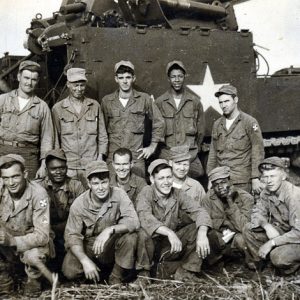 White and African-American soldiers posing in front of artillery