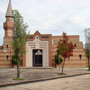Brick building with tall pointed tower and gate entrance