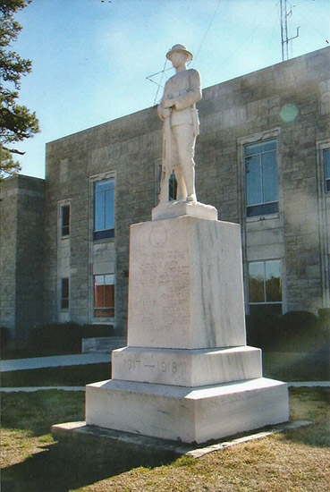 Statue of soldier on pedestal outside two-story brick building
