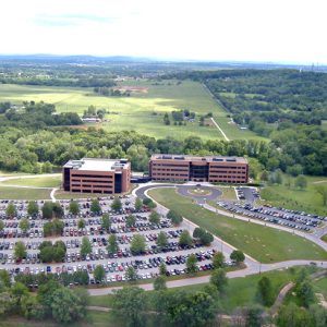 aerial view of two brick and glass buildings with large sprawling parking lot