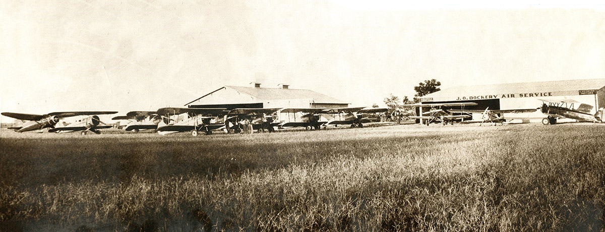 Line of biplanes and hangers at air field