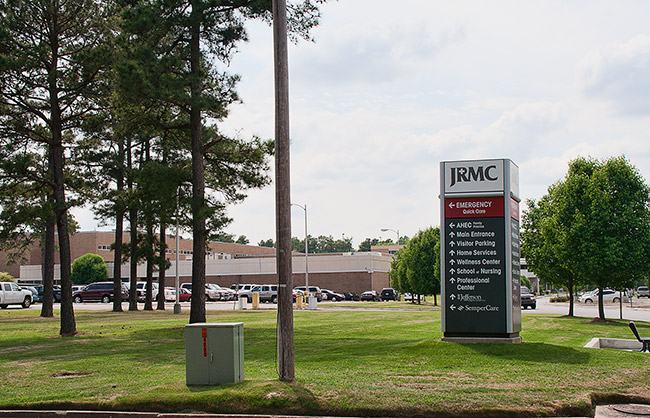 Brick building with "JRMC" sign parking lot and trees