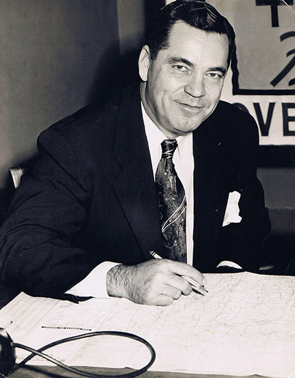 White man in suit and tie signing document