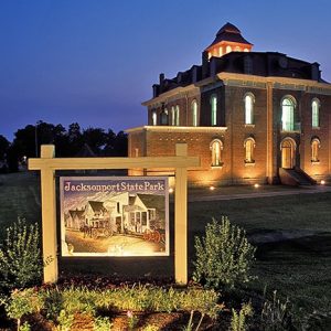 Three-story building with tower and sign "Jacksonport State Park" at night