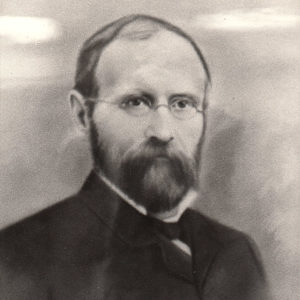 White man with beard and glasses in suit with bow tie