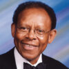 African-American man with glasses smiling in tuxedo