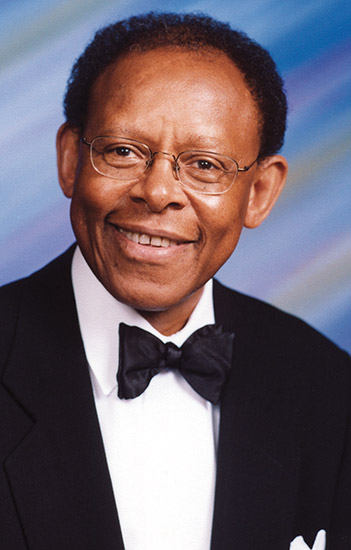 African-American man with glasses smiling in tuxedo