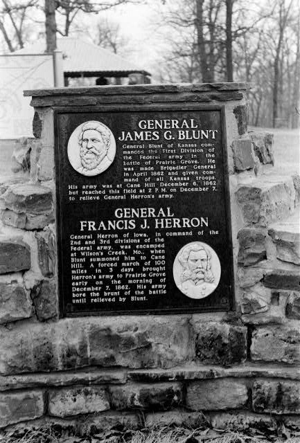 "General James G. Blunt" and "General Francis J. Herron" plaque with text and engraved portraits on it on brick wall