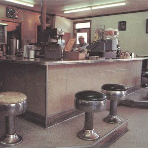 Employees and patrons at counter in cafe with circular seats