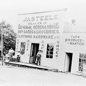 Two white men at "J.A. Steele" store front on dirt road