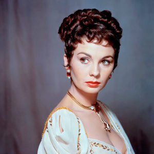 White woman with short curly hair in gold and white dress