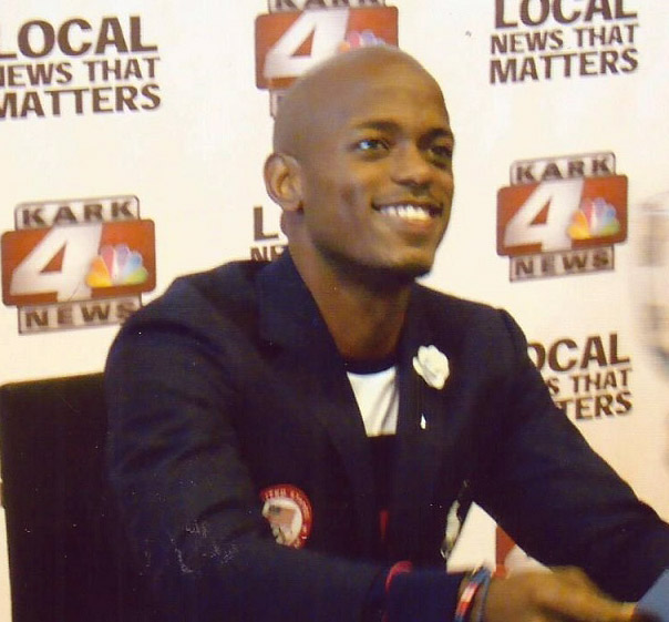 African-American man sitting and smiling in suit jacket