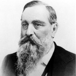 White man with long beard and mustache wearing a suit