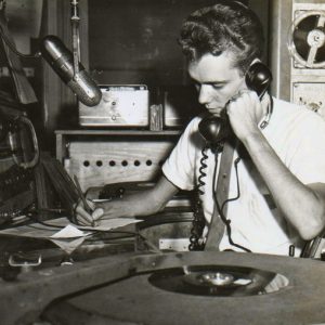 Young white man answering calls in radio booth