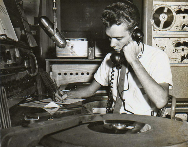 Young white man answering calls in radio booth