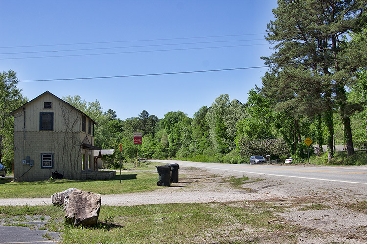 Multistory building and sign on rural road with trees on its right side