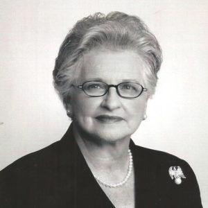 Older white woman with glasses in suit and pearl necklace