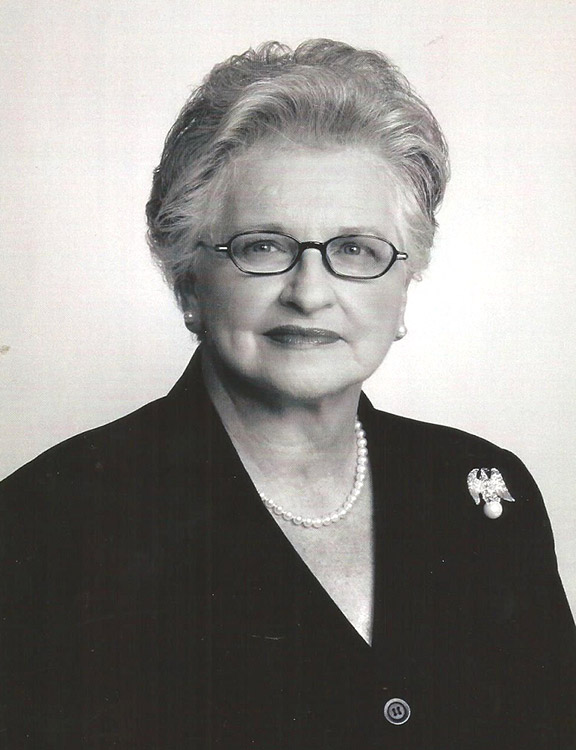 Older white woman with glasses in suit and pearl necklace