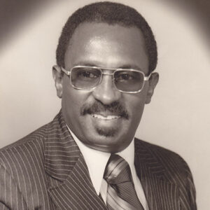 African-American man with mustache and glasses in suit and tie