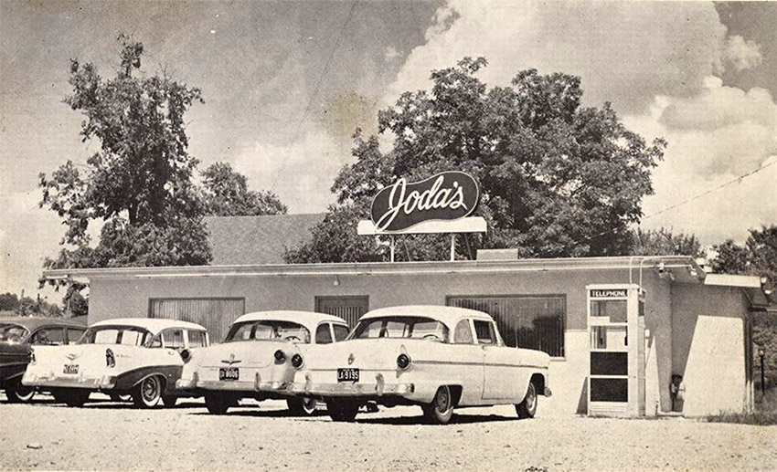 Cars and phone booth in front of restaurant "Joda's"