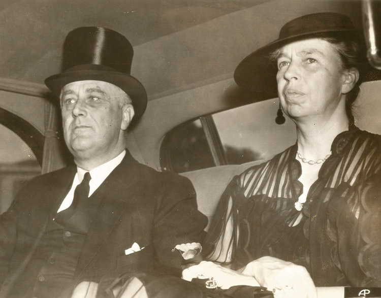 White man and woman in formal clothing in back seat of a car