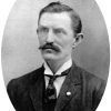 White man with mustache in suit and tie