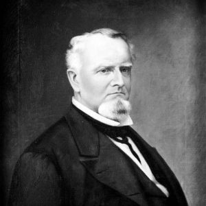 White man with white hair and beard in suit and tie
