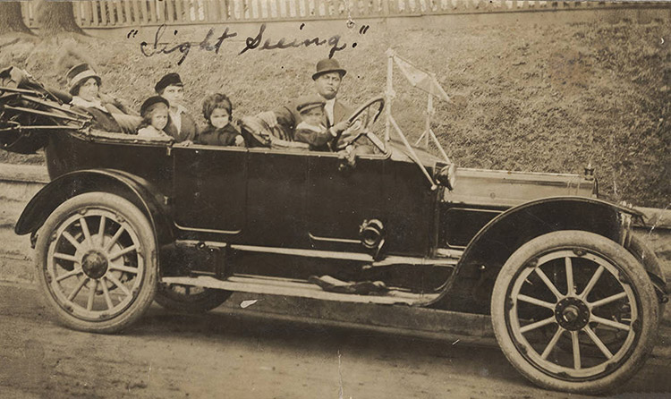 African-American man woman and children in convertible car with the top down signed "Sight Seeing" in ink