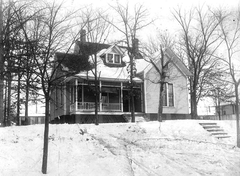 Multistory house with covered porch and trees in winter