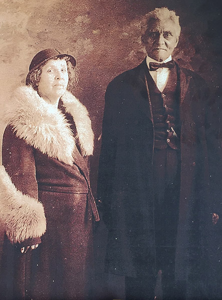 African-American woman in fur coat and hat standing with African-American man in suit and bow tie