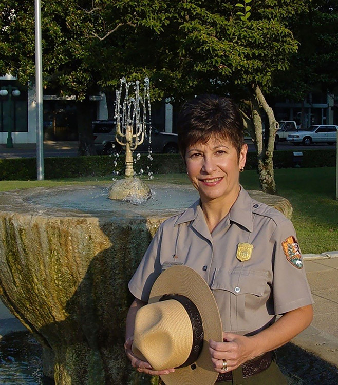 Hispanic woman in park ranger uniform smiling at fountain