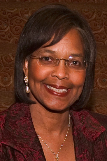 smiling black woman with straight hair glasses and necklace and earrings