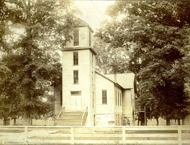 white wooden building with tower and stairs in front