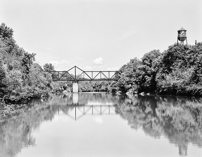 Steel truss bridge over river with concrete column