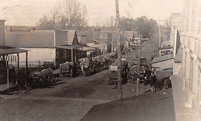 Storefronts and horse-drawn wagons on dirt road