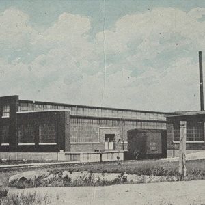 Brick warehouse buildings with train car in between them and dirt road in the foreground