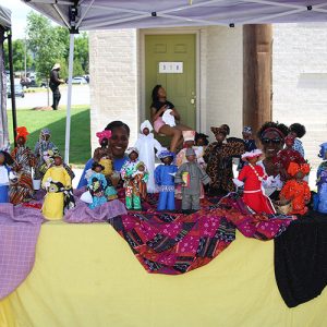 African-American women selling handmade dolls under tent canopy