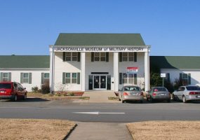 Two-story building with single-story wings and parking lot "Jacksonville Museum of Military History"