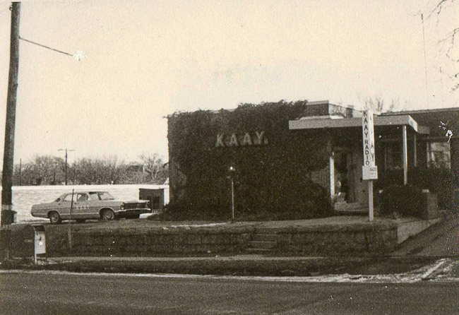 Car parked outside single-story "K.A.A.Y." building on street